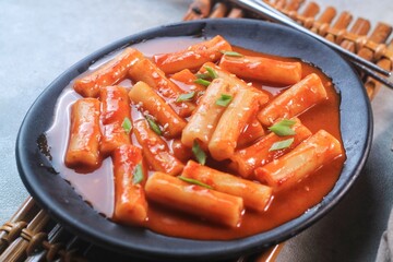 Delicious Korean Cuisine spicy tteokbokki or ttopoki on black plate. 