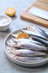 Fresh sardines, lemon and salt on kitchen, landscape shot.