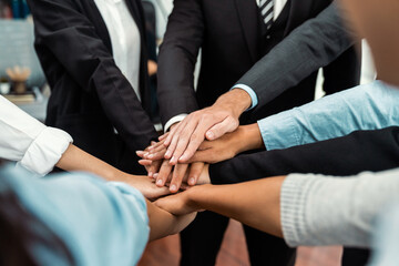 Obraz premium Multiracial business people make synergy hand stack together in meeting room as cooperation or team building for corporate employee in workplace. Meticulous