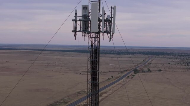 A communication tower in a vast texan landscape with a road, aerial view