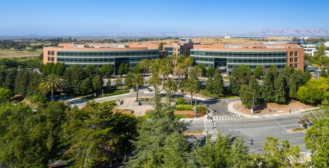 Aerial view of Googleplex office buildings, lush landscaping, and city streets. Sunny day, business...