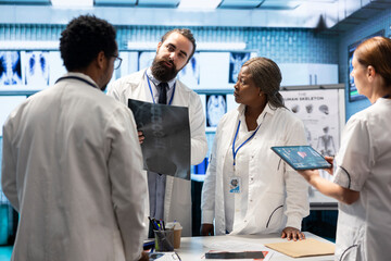Doctors and nurses analyze human anatomy scans results in a treatment center, putting the right diagnosis. Diverse team of healthcare experts working together on disease prevention, x ray tests.