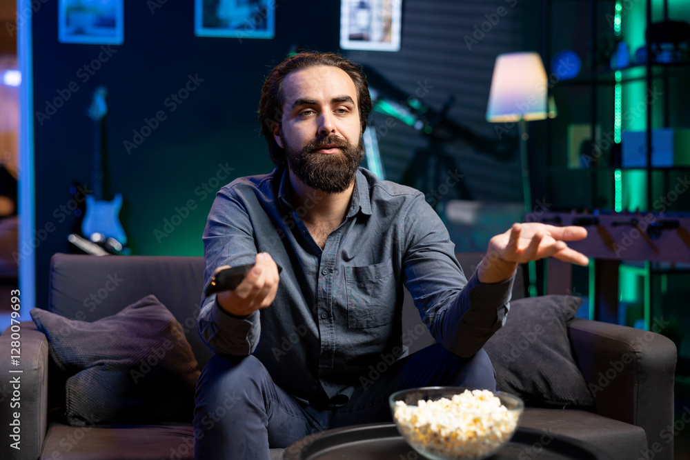 Poster man disagreeing with characters while watching movie on streaming services, having relaxing evening.