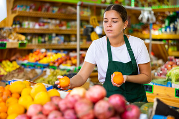 Portrait of cheerful woman marketer working at fruit department of store