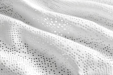 Close-up of white perforated fabric texture. Ideal for sportswear, apparel, or textile designs.