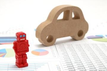 Business concept with miniature robot, car model, and financial graphs