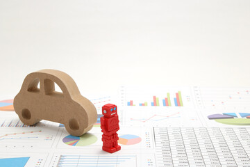 Business concept with miniature robot, car model, and financial graphs