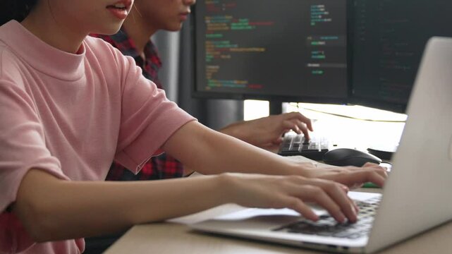 Slow motion back end software developer engineer for computer programming working together on debugging writing computing code, solving complex algorithms display on monitor in office. Burgeoning