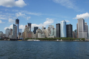 Fototapeta premium New York City skyline stretches across the calm blue water. Towering skyscrapers pierce the sky, a bustling metropolis reflecting in its urban beauty.