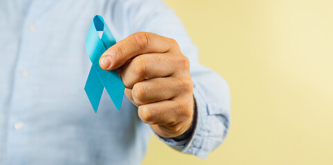 Holding a blue ribbon to raise awareness for men's health issues and cancer