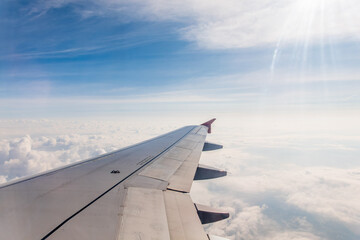 Fototapeta na wymiar View from the airplane window at a beautiful cloudy sky and the airplane wing
