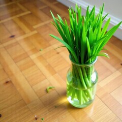 Fresh grass in a clear glass vase on a wooden floor with a few stray blades, green, grass, floor