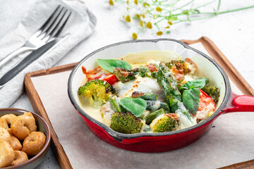 Baked broccoli, asparagus and tomatoes with mozzarella and parmesan cheese in a pan. Italian dish 