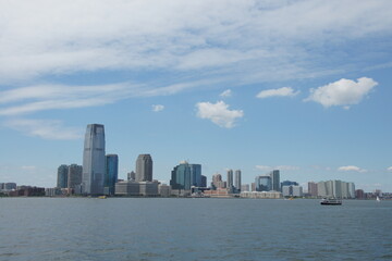 Fototapeta premium New York, Manhattan emerges from the Hudson River at sunset, bathed in a warm glow from a sky ablaze with orange, pink, and purple hues. A peaceful urban oasis.