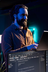 Joyful freelancer doing software debugging using laptop, checking errors in lines of code displayed...