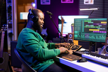 Confident music engineer working on mixing console in home studio, producing new sounds for a song...