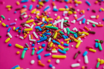 Fototapeta premium Colorful sprinkles scattered on a vibrant pink background, perfect for baking blogs, party invitations, or vibrant food photography.