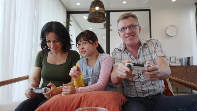 Granddaughter guide grandmother how to play console game with grandfather. Senior use technology activity communicate new generation kid cross generation gap strengthen family bond. Divergence.