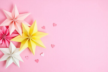 Pink and yellow origami flowers on pink background with small pink hearts