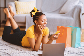 It's Time For Shopping. Smiling dreamy african american woman using laptop and looking at credit...