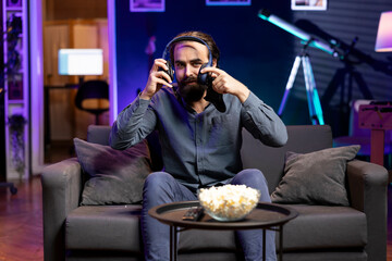 Smiling man putting headset on to play videogames in neon lit apartment, holding controller. Gamer...