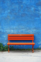 Empty orange bench against vibrant blue wall
