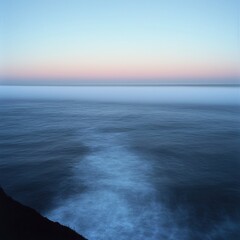 Obraz premium A tranquil sea landscape with fog rolling over the water in soft pastel tones during early morning light