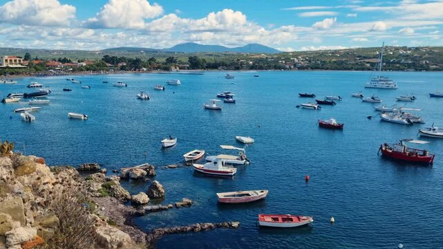 Panning shot over Methoni and its bay, Greece, with small fishing boats anchored in the blue Mediterranean Sea