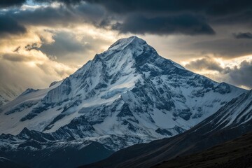 Fototapeta premium Majestic Snow-Capped Mountain Peak Under Dramatic Sky – Breathtaking Landscape Photography