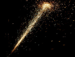 A bright, glowing firework trail is shot against a dark background © schankz