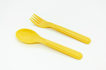 Yellow plastic picnic spoon and fork on white background, copy space