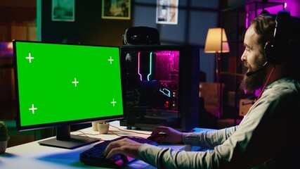 Man having fun by using green screen computer monitor to play singleplayer videogame. Professional...