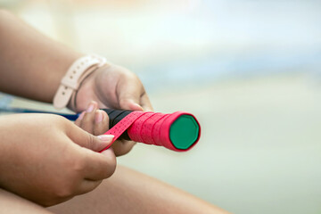 Woman replaces old winding on handle of badminton racket with new one. Replacement of old racket...