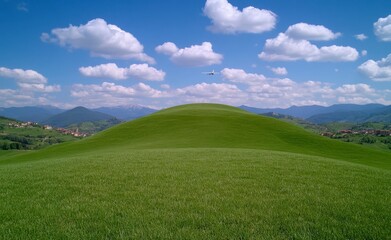 Fototapeta premium Lush Green Hill Under a Cloudy Blue Sky in a Rural Countryside Landscape