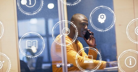 Image of media icons over african american casual businessman talking on smartphone in office