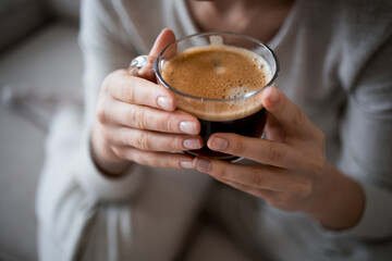 Female hands holding a cup of freshly brewed coffee at home
