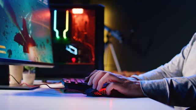 Man using gaming RGB lit mouse to shoot asteroids in spaceship flying videogame. Gamer using powerful PC and computer peripherals to compete in science fiction multiplayer game