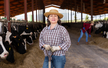 Portrait of confident successful adult spanish female farmer posing in cowshed