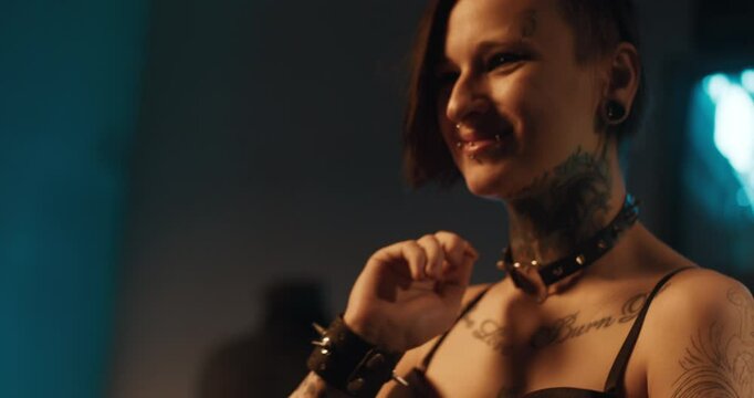 Individuality, and self-expression by tattoos and piercing, stay yourself. Young woman in informal clothes and patterns on body in dark room, seduction and temptation, sensual female sexuality