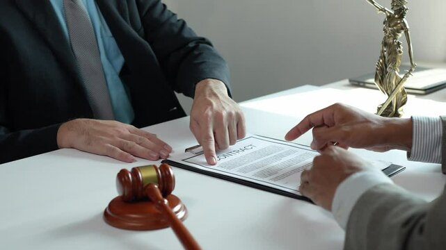 Professional lawyers carefully reviewing contract details during intense legal consultation, judicial gavel strategically placed on conference table signaling serious business negotiation process