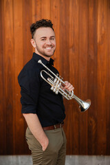 Smiling trumpet player against warm wood © Cavan