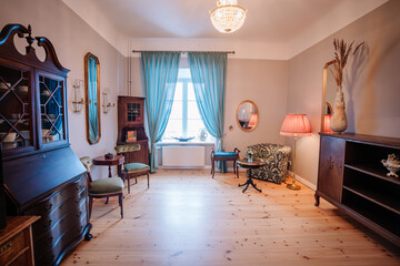 Elegant vintage living room with antique wooden furniture, soft lighting, blue curtains, and...