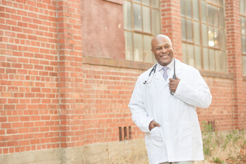 Confident doctor in a white coat standing outside, smiling