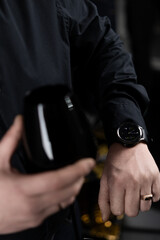Man in black shirt, watch on hand, gold ring on finger