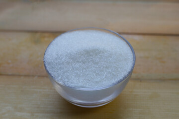 Monosodium glutamate in bowl on wooden background.