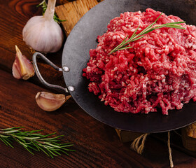 Fresh ground beef with garlic and herbs on wooden table