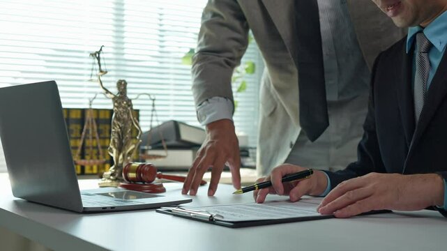 Legal professionals collaborate on a contract, carefully reviewing terms and conditions before signing, demonstrating expertise and attention to detail in a formal office setting