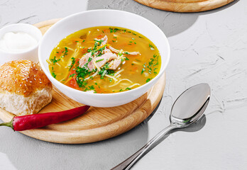 Delicious chicken noodle soup served with fresh bread and chili