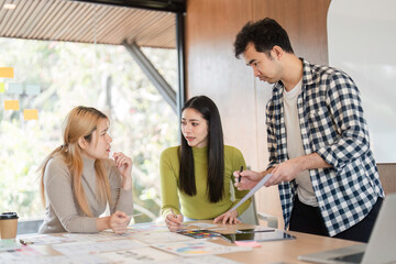 Diverse team deep in discussion while analyzing design materials in an office.