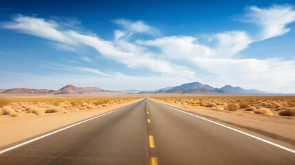 Naklejka premium Straight desert road flanked by mountains, clear blue sky, smooth asphalt, and dry grass, with a sense of freedom and journey.
